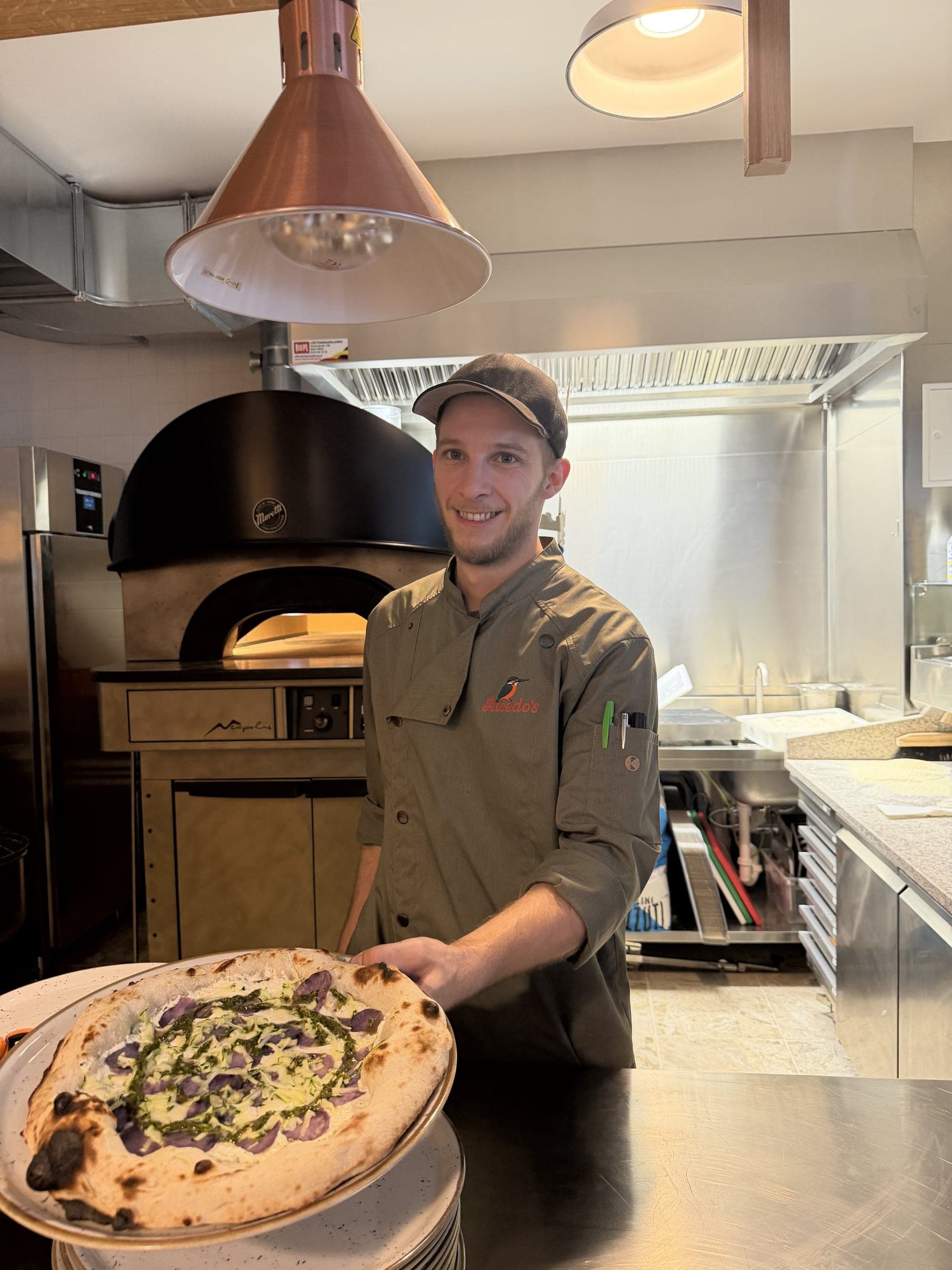 Pizzaiolo mit frischer Pizza vor dem Steinofen im Alcedo's Diner Graz
